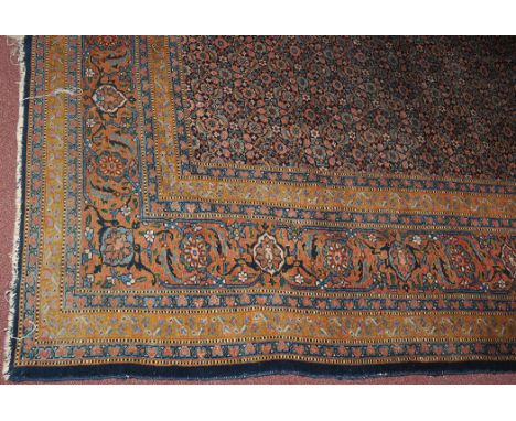 A Kirman carpet, the field decorated with multiple flowerhead designs surrounded by scrolling floral border, 175 x 151in. (44