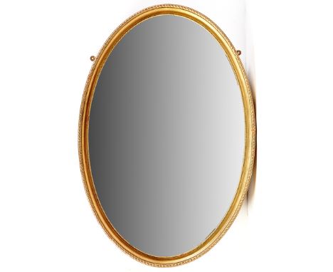 A gilt framed oval wall mirror, the bevelled glass surrounded by beadwork and gadrooned edge, 37 x 25in.
