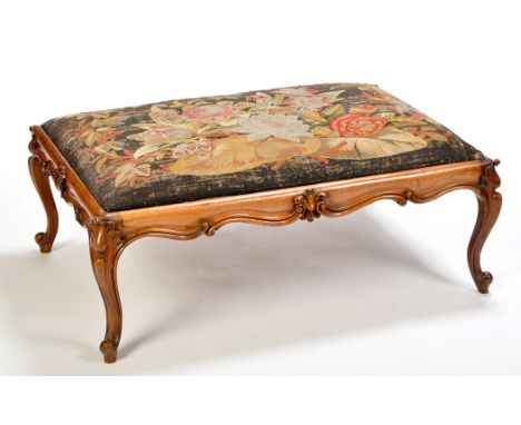 A Victorian rosewood stool, the drop-in cushion covered in floral needlework tapestry, above scrolling and leaf carved frieze