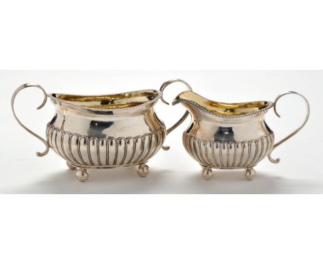 A George III two-handled sugar bowl and matching cream jug, possibly by Samuel Hennell, London 1810, with oval half fluted fo