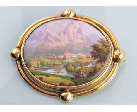 A 19th Century Swiss enamel and yellow metal brooch, the central plaque decorated with a mountain foot village, the yellow me