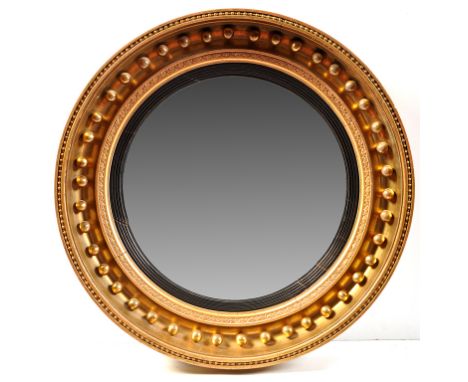 A Regency giltwood and gesso convex wall mirror, the circular plate within ebonised border, the giltwood frame decorated with