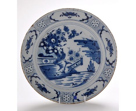 Delftware blue and white dish, the centre painted with female figure within chinoiserie garden landscape enclosed by floral c