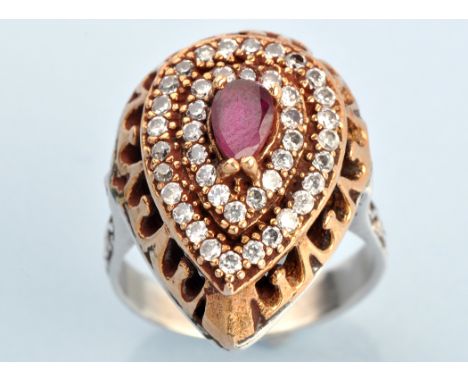 A ruby and diamond cluster ring, the pear-shaped mount with central facet cut ruby surrounded by two tiers of diamonds, on wh