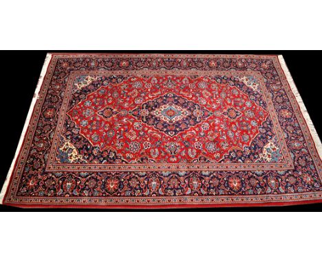 A Kashan carpet, the central floral medallion on red ground surrounded by loose floral scrolls, 118 x 79in. (300 x 200cms).