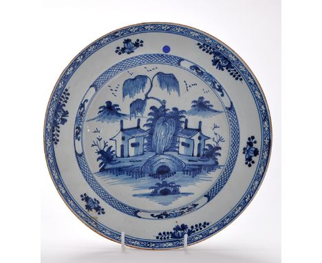 Delftware blue and white dish, the centre painted with two houses within chinoiserie landscape enclosed by lattice and cartou