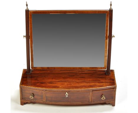 A George III mahogany toilet mirror, the rectangular plate on reeded supports with brass urn finials, the bowfront base fitte