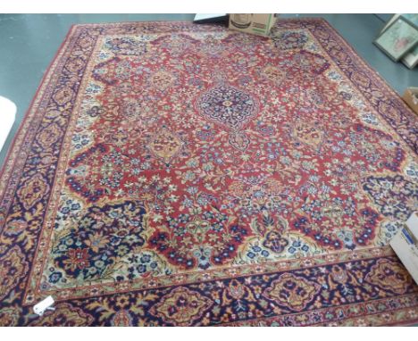 A Persian rug, red field, multiple floral border, with central scrolling floral pattern,