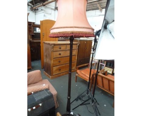 A painted wood standard lamp turned stem on circular base with red fringed shade
