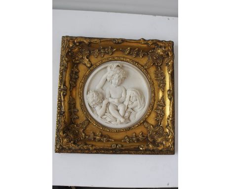 A marble style circular plaque depicting a cherub group, framed with an ornate gilt frame, 30 x 30cm