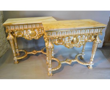 A Pair of French Cream Painted and Gilded Console Tables, each with a rectangular variegated marble top above a shaped frieze
