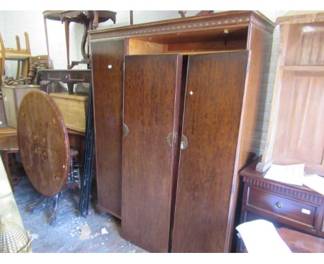 Mahogany three door wardrobe, circa 1930, the carved and moulded cornice above three panel doors with brass handles and escut