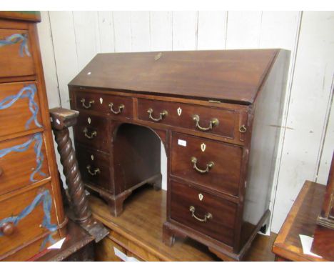 Early 19th Century mahogany knee hole bureau, the fall front enclosing a fitted interior above an arrangement of six short dr