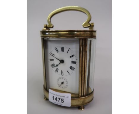 Late 19th / early 20th Century French brass carriage clock, the oval case enclosing an enamel dial with Roman numerals and su