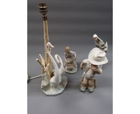 Lladro figure of a cowboy, two other Lladro figures and a Lladro style table lamp in the form of swans beside a tree 