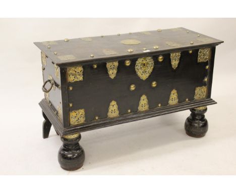 18th Century Continental ebonised brass mounted and studded trunk, the hinged moulded lid above a decorative panel front and 