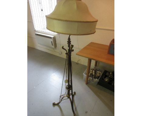 Early 20th Century brass standard lamp with three splayed supports, having paw feet and cream shade