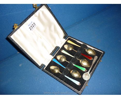 A presentation cased set of six silver gilt teaspoons having engine turned handles attractively enamelled in various striking