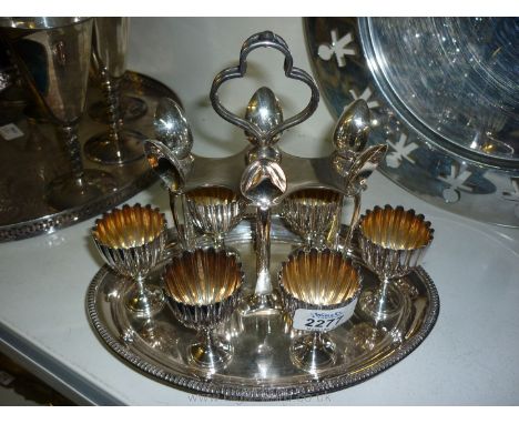 A silver plated egg cup stand with egg cups and spoons.