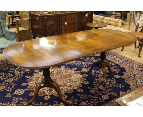 A George III mahogany pedestal extending dining table, twin pedestal curved ends with an extending leaf, raised on a turned g