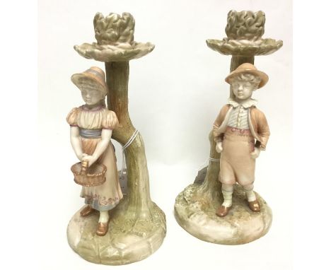 A pair of Royal Worcester figural candlesticks, one depicting a male, the other depicting a female holding a basket, height a