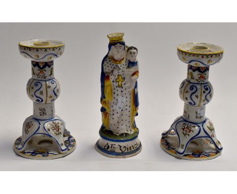 A pair of French Quimper candlesticks, together with a religious Quimper figure. (3)