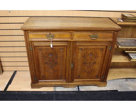 A 20th century oak carved sideboard, rectangular moulded top, above two short drawers with brass handles, above two panel car