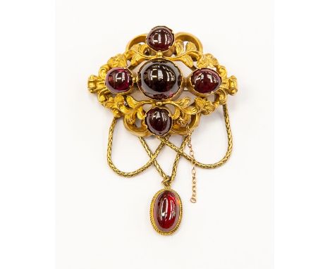A Victorian garnet brooch, comprising four cabochon cut garnets within a surround of scroll and leaf decoration, with suspend