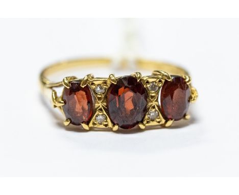 A Victorian 18ct gold three stone garnet ring, diamond accents, size S, total gross weight approx 3.7gms