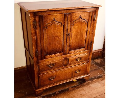 A tradtional oak cupboard, 20th Century, double ogee moulded panel doors, two short and one long drawer below raised on carve