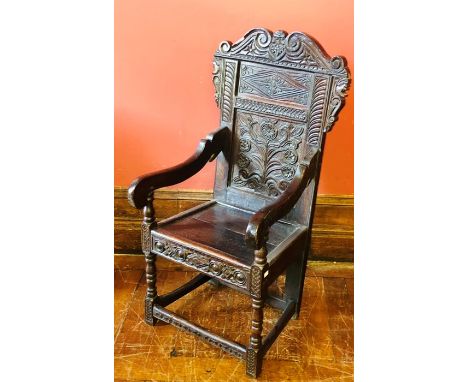 A 17th Century revival oak wainscot chair, scrolling carved top, foliage decorated panel back, moulded seat, raised on balust