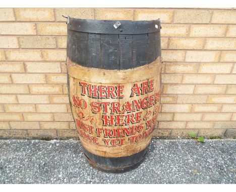 A vintage half barrel, formerly used as decoration in a public house with hand painted motto 'There Are No Strangers Here, Ju