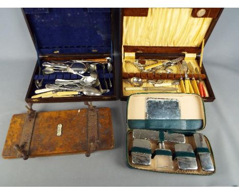 Two cutlery canteens with predominantly plated contents, a travel grooming set and a vintage tie press.