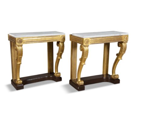 A PAIR OF WILLIAM IV GILTWOOD CONSOLE TABLES, the moulded friezes raised on leaf carved scroll legs on mahogany platform base
