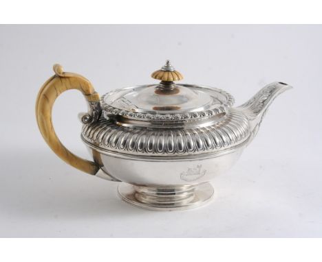 A GEORGE IV SQUAT CIRCULAR TEA POT with an ivory handle & finial, a part-fluted upper body & a leaf wrapped spout, crested, b