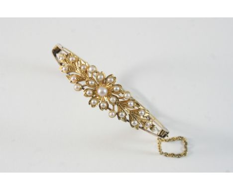 A VICTORIAN PEARL AND GOLD HALF HINGED BANGLE the foliate decoration set with small pearls, in 15ct. gold. With box.