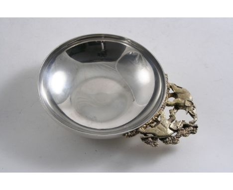 BY STUART DEVLIN: A contemporary parcelgilt nut dish, plain circular with a flat base, the openwork handle cast in the form o
