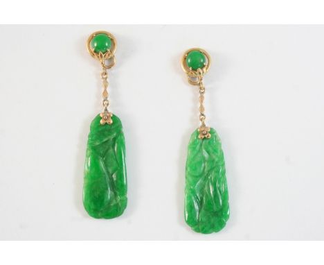 A PAIR OF CARVED JADE DROP EARRINGS each set with a section of carved jade suspended from a circular jade cabochon in gold, 5