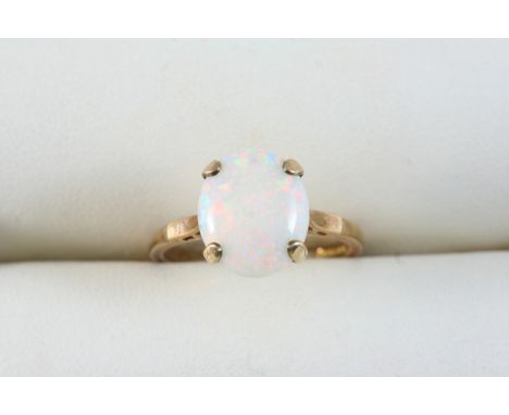 AN OPAL SINGLE STONE RING set with an oval-shaped cabochon white opal, in gold. Size O.