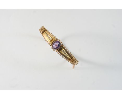 AN EARLY 20TH CENTURY AMETHYST AND GOLD BANGLE set with an oval-shaped amethyst and with small graduated pearls, in 9ct. gold