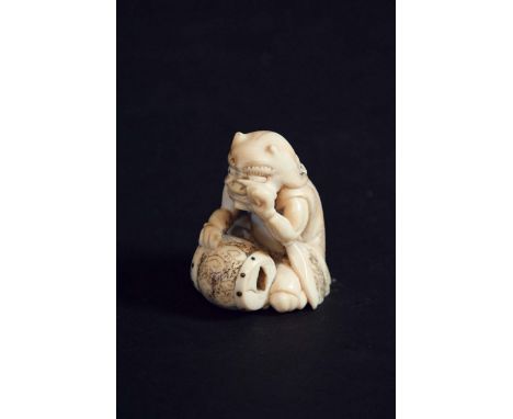 AN IVORY NETSUKE of a seated demon drummer, engraved details