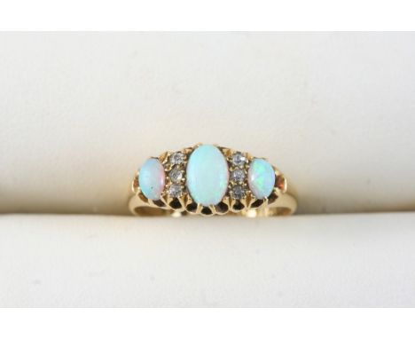 AN OPAL AND DIAMOND RING set with three graduated oval cabochon opals and six circular-cut diamonds, in 18ct. gold. Size O.