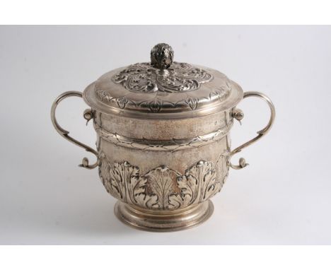 A LATE VICTORIAN TWO-HANDLED CUP & COVER in the Charles II style, with embossed stiff leaves around the lower body & a bud fi