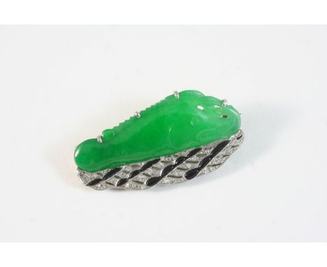 AN ART DECO JADE, DIAMOND AND BLACK ONYX BROOCH the green jade plaque is carved and pierced in the form of a fish and set wit