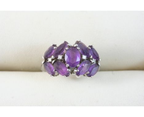 AN AMETHYST AND DIAMOND RING centred with an oval-shaped amethyst, within a surround of marquise-cut amethysts and small diam