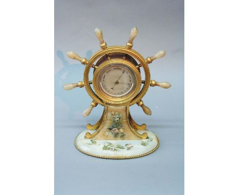 AN ORMOLU SHIPS WHEEL BAROMETER the silvered dial set with a crescent thermometer, the beaded wheel with banded alabaster han