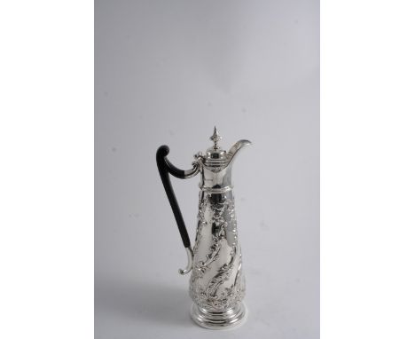 AN EDWARDIAN HOT WATER JUG OR EWER with an elongated, tapering body embossed with swirling foliage, knop finial, maker's mark