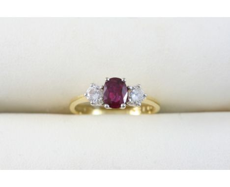 A RUBY AND DIAMOND THREE STONE RING the oval-shaped ruby is set with two circular-cut diamonds, in 18ct. gold. Size L.