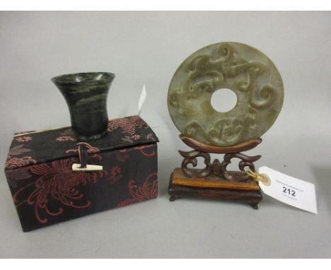 Chinese circular carved jade disc mounted on a hardwood stand (at fault), together with a Chinese jade luminescent cup 