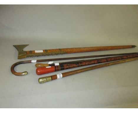 Walking cane with the Queens Regiment finial, a walking cane with axe head, a lacquered walking cane and two others 